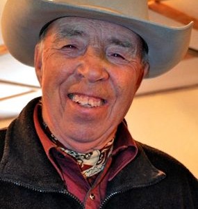 Man wearing cowboy hat, smiling.