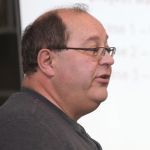man speaking at podium microphone