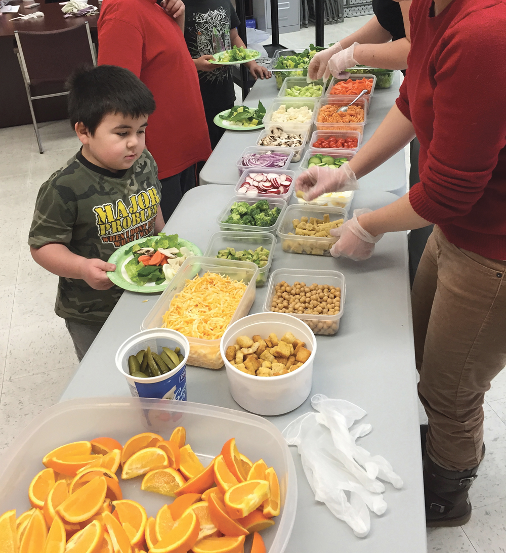 A young man attending Alonsa Community School surveys the snack foods served at school, including veggies grown in the school’s own gardens.