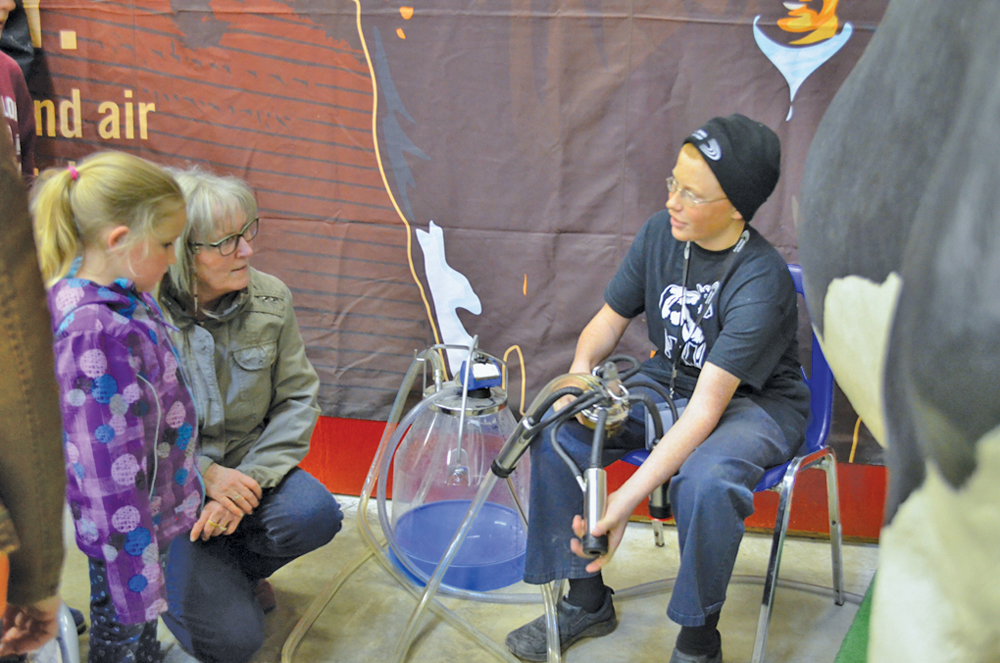 Lucus Vanderkamp, who travelled from his dairy farm that’s located 20 miles east of Beausejour to work at the Royal Manitoba Winter Fair dairy demonstration, explains the process of milking a cow to fair attendees.