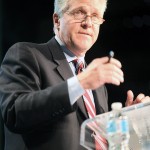 Man presenting on stage with microphone.