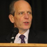 man at podium speaking into microphone
