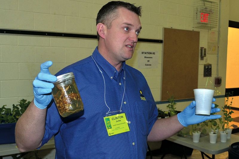 Man holding canola samples in jar.