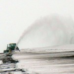 Farmer blowing snow with a tractor.