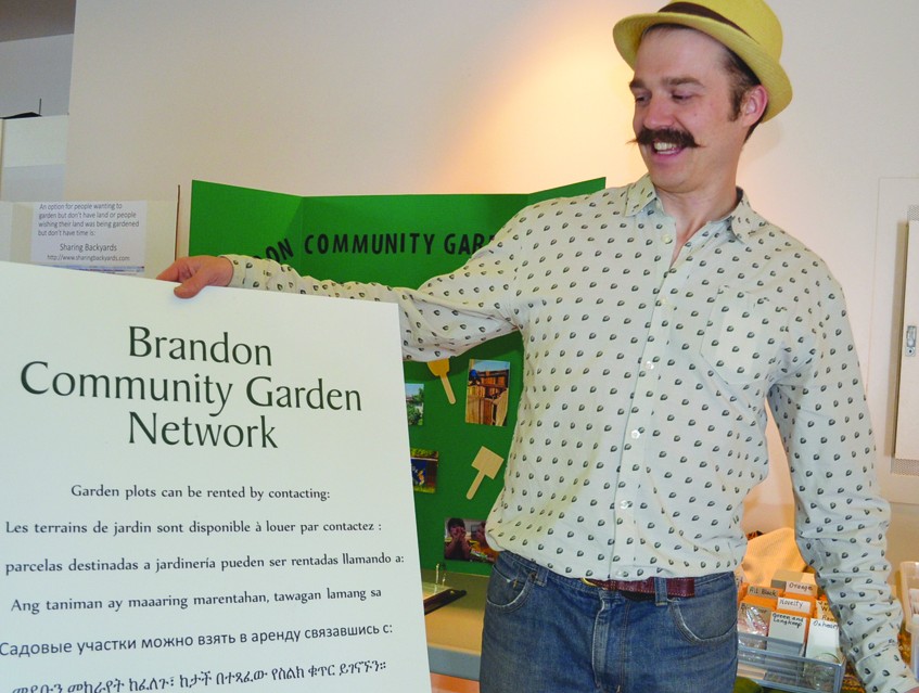 Man showing multilingual sign for community gardeners.