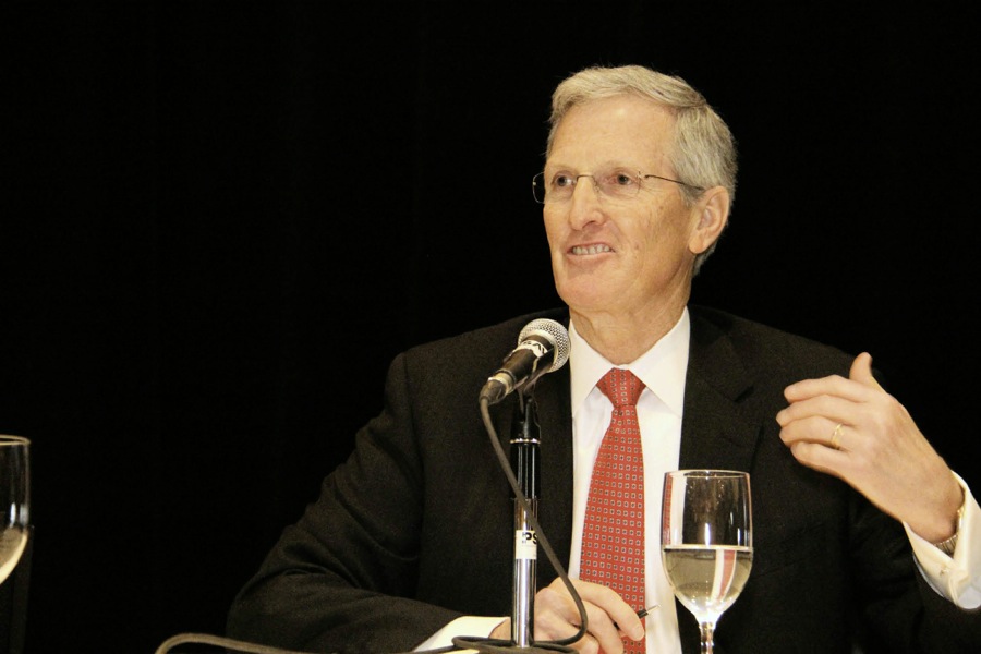 Mature man speaking into microphone at a conference.