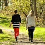two women walking along a treed path