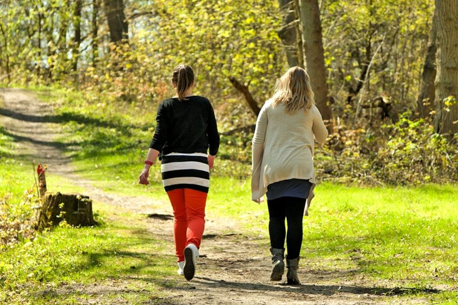 two women walking along a treed path