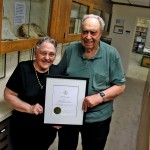 Elderly couple holding award.