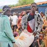 man and woman carrying a bag of rice