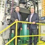 two men standing in an agricultural seed treatment facility