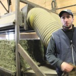 man standing beside hay-baling machinery