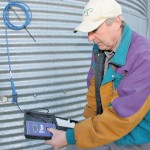 man checking moisture content in a canola bin