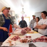 Greg Wood gives a butchering demonstration as Talia Syrie and others look on.