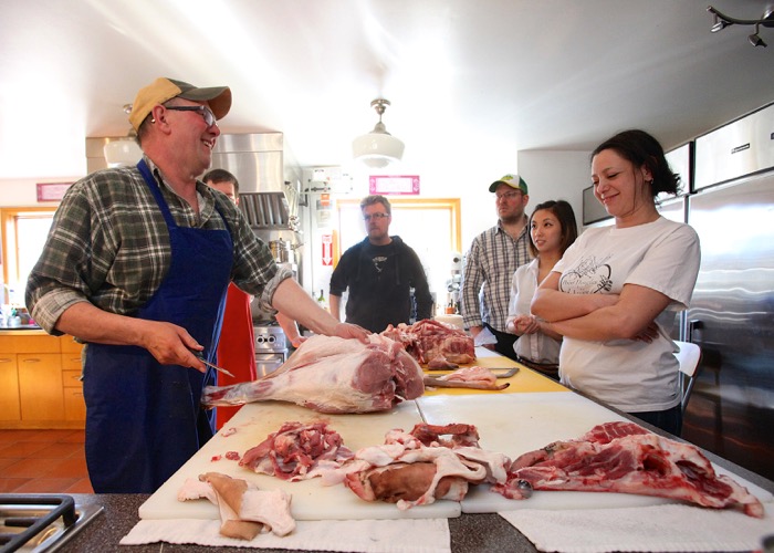 Greg Wood gives a butchering demonstration as Talia Syrie and others look on.