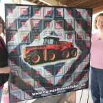 Manitoba Agricultural Museum’s executive director Georgette Hutlet (l) and curator Tanya Wiegand display the museum’s new barn quilt sign, to hang on the fence of the Austin-area museum.
The pattern is a version of the Log Cabin block and is emblazoned with one of the museum’s most popular artifacts, Big Roy, a Versatile Model 1080.