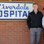 two men standing in front of brick building