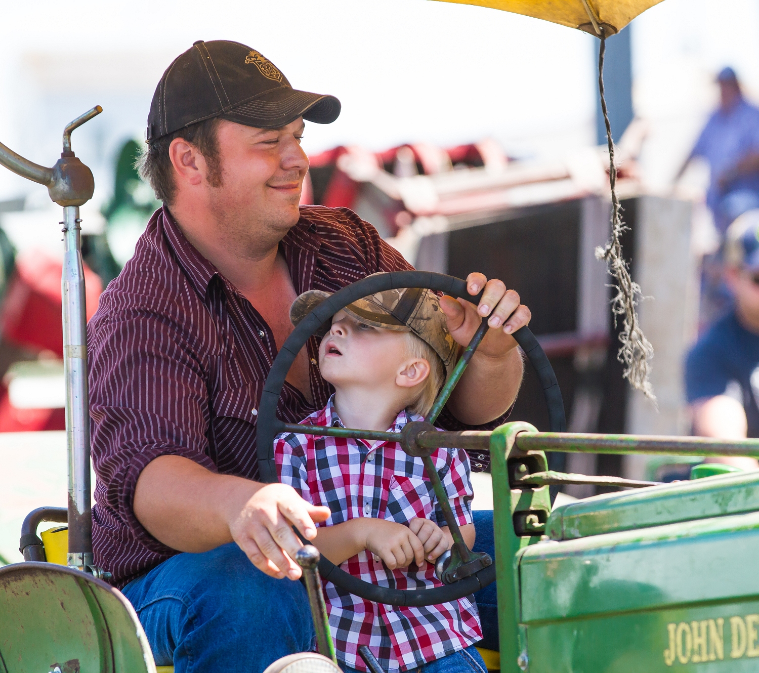 Richard Jackson and his son enjoy a ride on a 1947 John Deere under a umbrella during the daily parade.