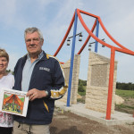 Merle Tomyk, secretary treasurer and Doug Pickell, chair of the Stonewall-Rockwood Kurelek Tribute Citizens Committee hold a calendar with “The Manitoba Party” painting of William Kurelek. Their committee will unveil a monument in honour of William Kurelek August 23. The monument was designed to look like the tent in the painting.