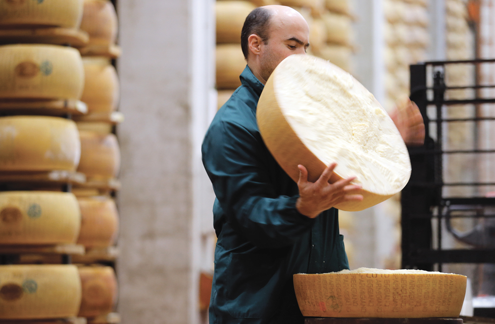 A worker opens a Parmesan cheese wheel at a warehouse owned by Credito Emiliano bank in Montecavolo, near Reggio Emila, central Italy.