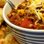 Chili with cheese and a spoon with biscuits on the side