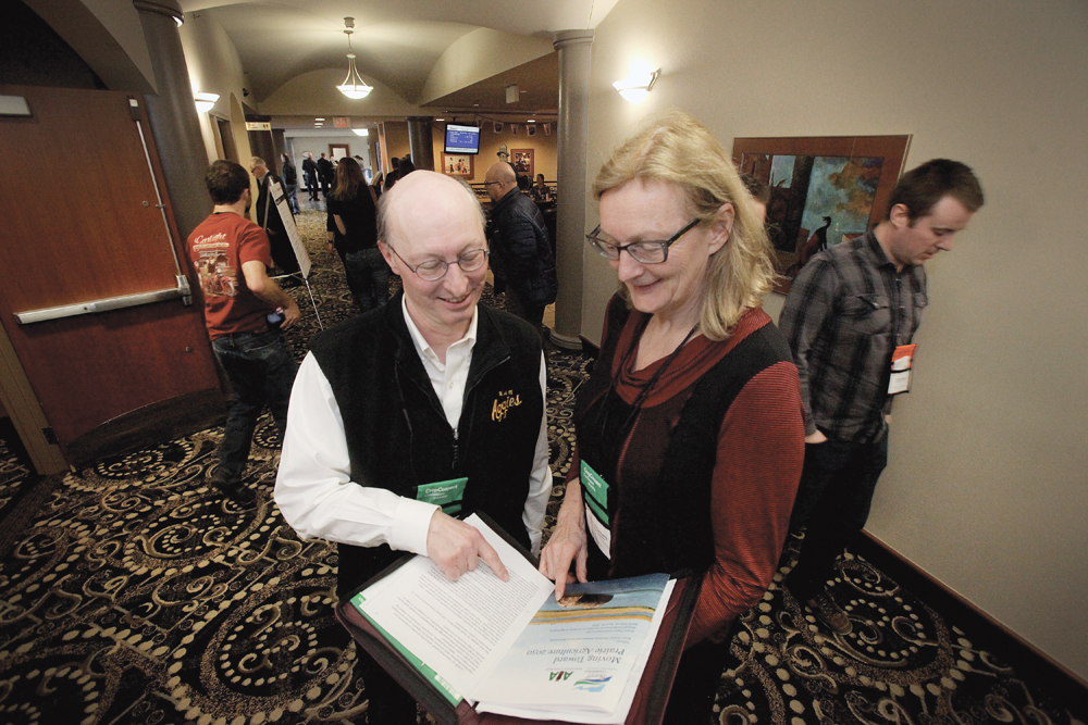 Brian Amiro and Karin Wittenberg look over their presentation at Crop Connect in Winnipeg.