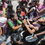 Local residents fight to collect free drinking water from municipal corporation tanker on a hot summer day on the outskirts of Ahmedabad.