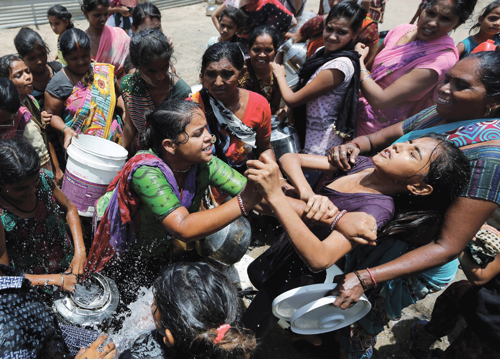Local residents fight to collect free drinking water from municipal corporation tanker on a hot summer day on the outskirts of Ahmedabad.