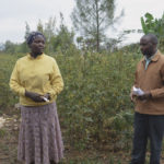 Lillian Wambui talks about her farm in front of a field of pigeon peas.