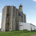 Built between 1979 and 1980 as an experiment by Manitoba Pool Elevators, the concrete elevator at Quadra, near Miniota, has 16, six-sided silos providing a total capacity of 150,000 bushels. In 1987, a wooden grain elevator from Kenton, built in 1967, was moved beside it to provide additional storage space. The facility closed in 2002 and the annex was demolished in late 2003. In 2006, the elevator was sold to a local farmer who rebuilt a 17-car rail spot and uses it for storage and shipping.