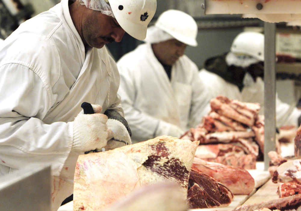 Workers bone and cut beef at a meat-packing plant in Toronto.