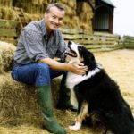 Farmer Sitting on a Bay of Hale on a Farm With His Pet Dog
