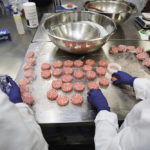 Workers assemble the plant-based hamburger patties during a media tour of Impossible Foods labs and processing plant in Redwood City, California.