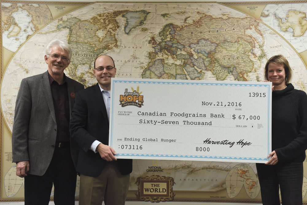 The record-setting Harvesting Hope event at Austin July 31, 2016 raised $134,000, which is being split between the Canadian Foodgrains Bank and the Manitoba Agricultural Museum. Barbara MacDonald director of international programs for the Canadian Foodgrains Bank, (right) accepts a $67,000 contribution from Elliot Sims, one of the organizers of the July 31 event, Harvesting Hope: A World Record to Help the Hungry. Also pictured (at left) is Harold Penner, Canadian Foodgrains Bank regional representative.