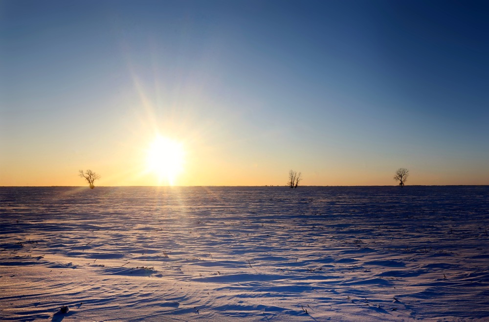 The sun sets over frozen prairie fields near Rosser, Manitoba as temperatures dip below -30 degrees Celsius in mid-December.