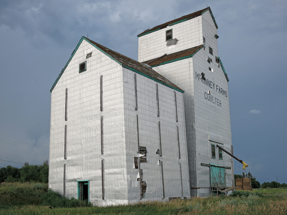 A 50,000-bushel grain elevator at Coulter, on the CPR Lyleton  Subdivision in the RM of Two Borders, with its associated crib annex and  engine shed, was once operated by Manitoba Pool. Built in 1928, it  closed in July 1971. Rail service ceased when a bridge was washed out  during a severe storm and was not replaced. The elevator was purchased  by a local farmer and used for private grain storage. This photo was  taken in July 2016.