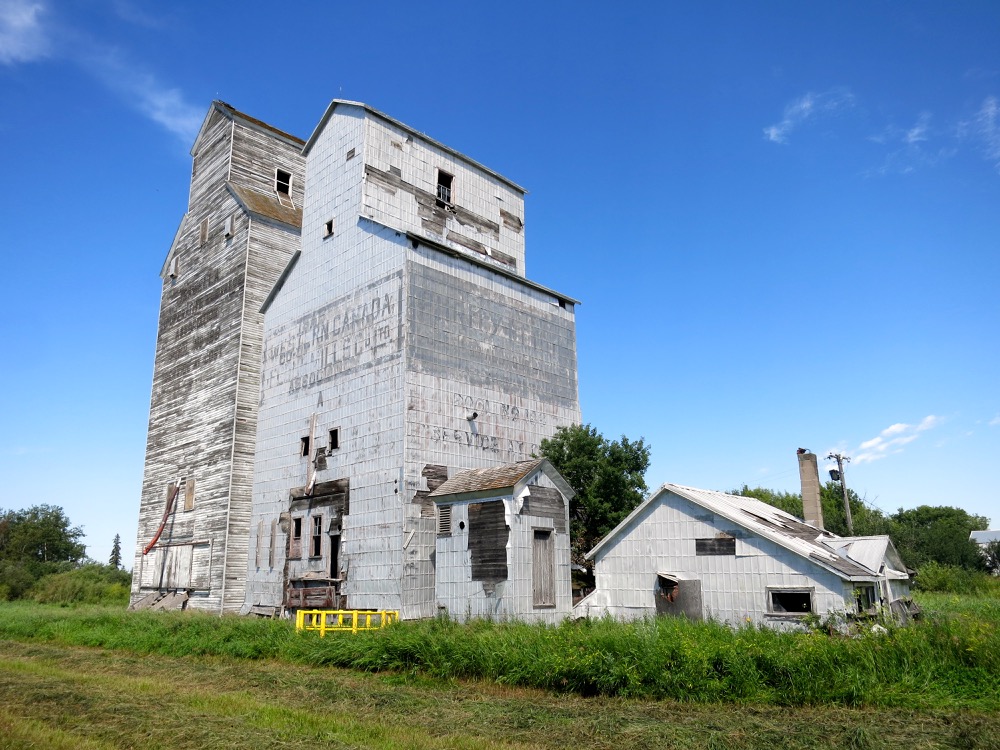The shorter of two elevators in Isabella, in the RM of Prairie View, was built in 1910 by the Western Canada Flour Milling Company and sold to Manitoba Pool in 1939. The taller elevator was constructed in 1913 by the Grain Growers’ Grain Company (later UGG) and operated until 1962 when it was traded to the Pool. The elevators were some distance apart but Pool moved the former UGG elevator next to its elevator and built a common driveshed between them. They closed in December 1978 as the adjacent CNR line was abandoned. Sold to a local farmer and used for grain storage into the 1990s, they are now in poor structural condition.