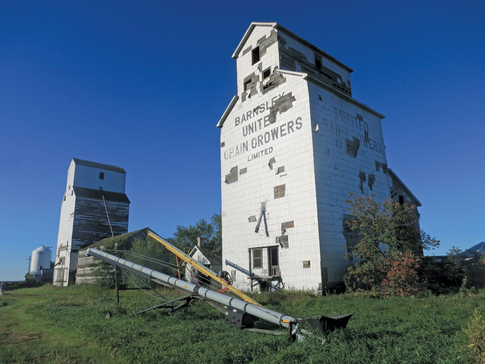 Two grain elevators at the former railway siding of Barnsley, in the RM  of Dufferin north of Carman, were once operated by Manitoba Pool. “Pool B” (right) was constructed before 1916 by the provincial government as  one of about 40 it built between 1910 and 1923 under the auspices of  its Manitoba Elevator Commission. The elevator was leased to United  Grain Growers in 1916 and sold to the Pool around 1959, which built  “Pool A” (left) in 1928. The two elevators were closed in July 1972 and  sold to a local farmer. Both are now in poor structural condition.