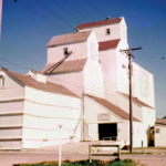 A 35,000-bushel grain elevator in Grandview, seen here in 1969, was built around 1920 by United Grain Growers. An annex built during the Second World War was used for nearly 40 years. In 1953, a new 70,000-bushel elevator was built beside the older elevator, replacing a flour shed and coal bins at the site. A 125,000-bushel cribbed annex was built beside the new elevator in 1961 and, 10 years later, the older elevator was repaired and converted to an annex. The wartime annex was demolished in 1981 and later the old elevator annex. The remaining structure closed on July 1, 2000 and was demolished in late November 2000. Grandview’s last elevator, built in 1950 by Manitoba Pool, was demolished in November 2009.