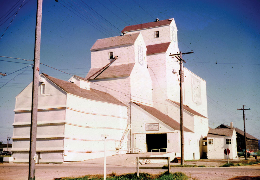 A 35,000-bushel grain elevator in Grandview, seen here in 1969, was built around 1920 by United Grain Growers. An annex built during the Second World War was used for nearly 40 years. In 1953, a new 70,000-bushel elevator was built beside the older elevator, replacing a flour shed and coal bins at the site. A 125,000-bushel cribbed annex was built beside the new elevator in 1961 and, 10 years later, the older elevator was repaired and converted to an annex. The wartime annex was demolished in 1981 and later the old elevator annex. The remaining structure closed on July 1, 2000 and was demolished in late November 2000. Grandview’s last elevator, built in 1950 by Manitoba Pool, was demolished in November 2009.