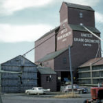 When this United Grain Growers elevator at Neepawa was photographed in 1961, it was surrounded on three sides by annexes, giving it a total capacity of 152,000 bushels. Three annexes were built as emergency storage space in August and September 1940, during the Second World War, when Nazi submarines threatened grain shipments overseas. Many of the annexes remained in service for decades and were cursed by generations of elevator agents. One of the wartime annexes was torn down in 1948, a second in 1978, and a third in 1980. The elevator, built in 1938, was demolished in November 2002.
