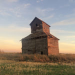 A small, wooden elevator in a field east of highway No. 242, south of La Riviere, is thought to have been built in the 1890s by Diggory Windsor and his brothers. It stood in their farmyard along with a brick house and shanty barn. A stationary engine and flywheel attached via the north side of the elevator drove its leg. The cupped belt lifted the grain to one of five bins, each holding about 1,200 bushels. By the 1970s, an external auger was used. Around 1979, the owner stopped using the elevator because its capacity was too small. It is slated for demolition due to concerns about rotten wood in its north wall.