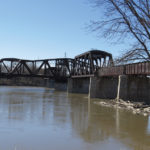 Some 100 years after it was constructed and 80 years after it was abandoned, the Bergen Cut-Off rail bridge remains spanning the Red River. The photo shows clearly the swing portion of the bridge which has been left in the open position so as to allow vessels on the river to move through. However, it has been a number of years since any vessels big enough to warrant the bridge being open have operated in this area of the Red River. Given it has been probably decades since the bridge saw any maintenance,  it appears to be in good condition and is a tribute to the contractors who built the structure.