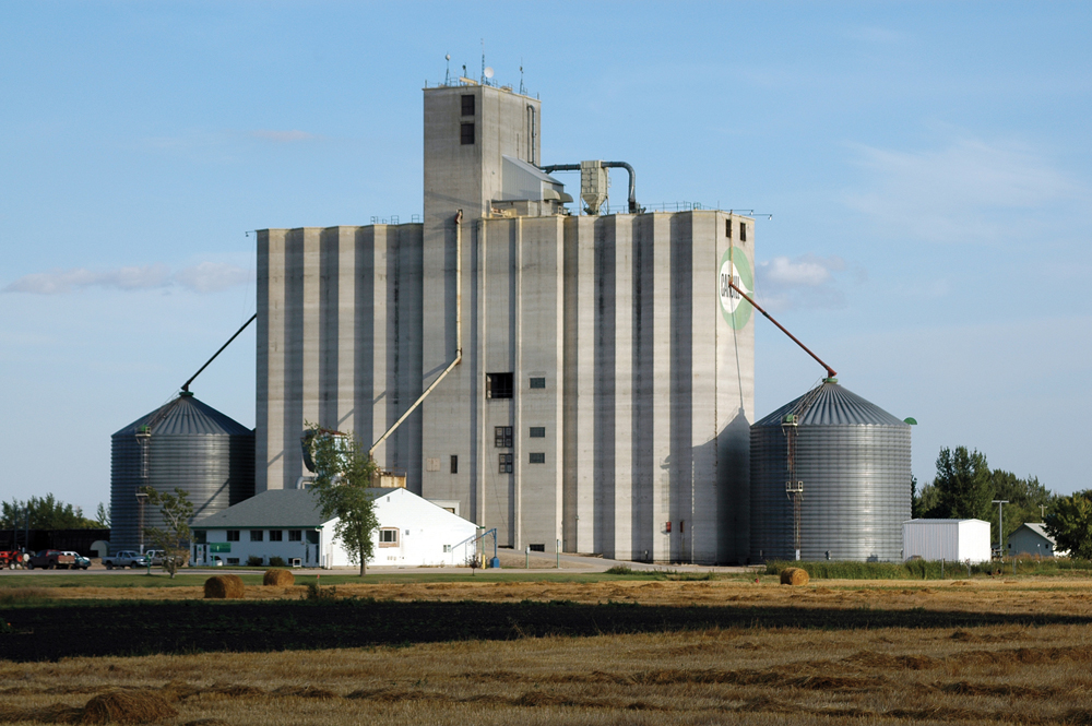 The Cargill elevator at Elm Creek is considered the “granddaddy” of the concrete terminals that now dominate the Prairie landscape. Built in 1976, along with an identical twin at Rosetown, Saskatchewan, the elevator had an initial 460,000-bushel capacity, by far the largest of any country elevator in Manitoba at that time. It had been built using a  slipform process that was increasingly popular for the construction of large, concrete structures across Canada, including Toronto’s CN Tower. The elevator’s capacity was increased over 40 per cent over the next few years but it is now dwarfed by other terminals up to five times its size.