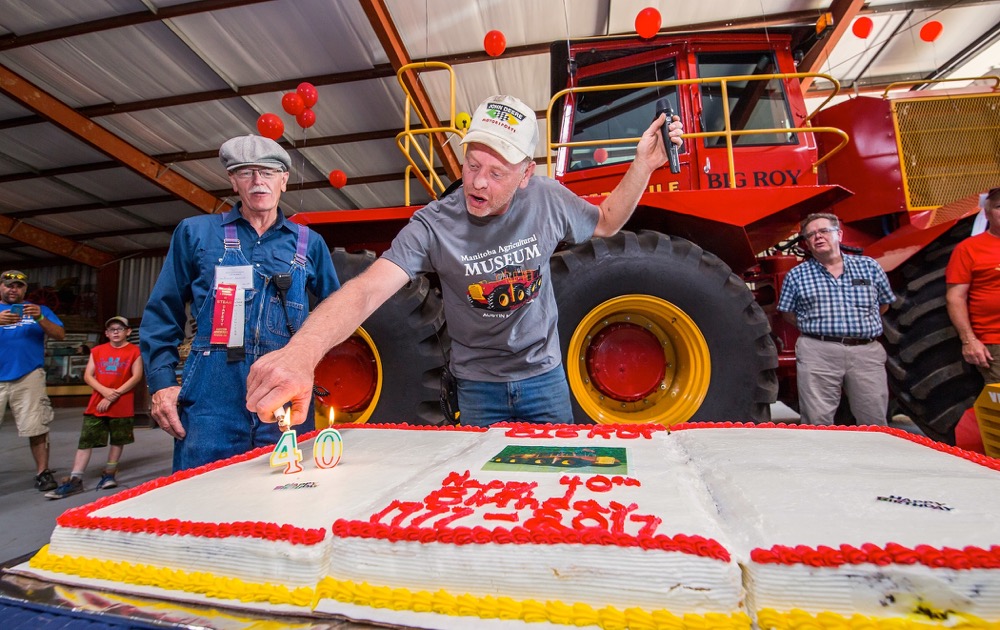 Dwayne Moorehead of Douglas, Man., operator and adoptee of the Versatile 1080 tractor known as Big Roy, lights the 40th birthday candle at the Thresherman's Reunion in Austin. Restored in 2016, the 30-foot, 600 horsepower tractor was built in 1977 and has been kept at the museum since 1979. Looking on (l-r) is Robert Beamish of Hamiota and Alex Campbell of Austin.