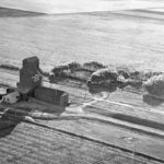 A 40,000-bushel wooden grain elevator at the railway siding of Graham, on the CPR Carman Subdivision in the Rural Municipality of Roland, was built in 1927 by Manitoba Pool Elevators. Closed in July 1971, the railway was abandoned in November 1975. No vestige of the railway tracks, elevator, agent’s residence, or access roads remain at the site in the middle of an agricultural field. This aerial view was provided by Doreen Smith whose husband Ralph was its agent from the mid-1940s to 1961.