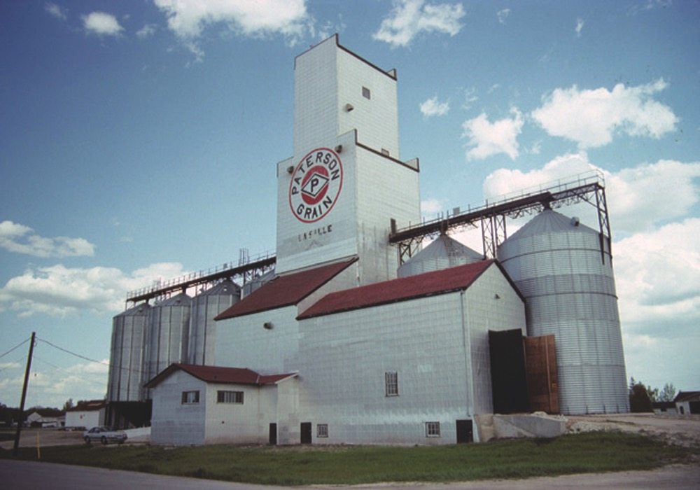 A 30,000-bushel elevator at La Salle, on the CPR La Riviere Subdivision in the Rural Municipality of Macdonald, was built in 1938 by the Paterson Grain Company using materials salvaged from a demolished elevator at Dumas, Saskatchewan. It replaced an earlier elevator built around 1912 by local farmer Moise Cormier and sold to Paterson in 1916. Balloon annexes were built beside the elevator in 1940 and 1955, increasing its capacity to 89,000 bushels. The annexes were subsequently replaced by six steel tanks between 1986 and 1988. Operated by a part-time manager, the facility is used to store beans.