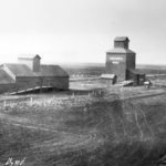 This historically significant photo of Niverville was taken in 1910, when three generations of grain-handling facilities were standing together. On the right was the first elevator in Western Canada, a round 25,000-bushel facility built in 1878 by William Hespeler of Winnipeg, to receive grain from newly arrived Mennonite farmers. On the left is a “flat” grain warehouse, a horizontal type that was once common across the Prairies. They were quickly replaced by more efficient vertical elevators. This one was used as a community hall from 1929 to 1963. In the centre is a 27,000-bushel elevator built in 1904 by Ogilvie Flour Mills and dismantled in 1938 to make way for a new 35,000-bushel elevator.