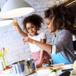 Beautiful African American woman and her daughter cooking in the kitchen