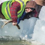 Aaron Sawatsky of Ninette checks the condition of one of the released fish in the release pond cut into the ice.